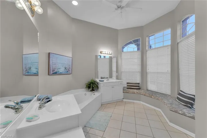 Bathroom featuring tile patterned flooring, vanity, ceiling fan, and a bathing tub