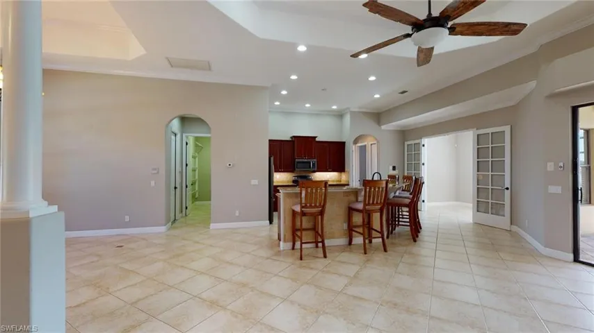 Kitchen with ornate columns, a breakfast bar area, ornamental molding, and ceiling fan