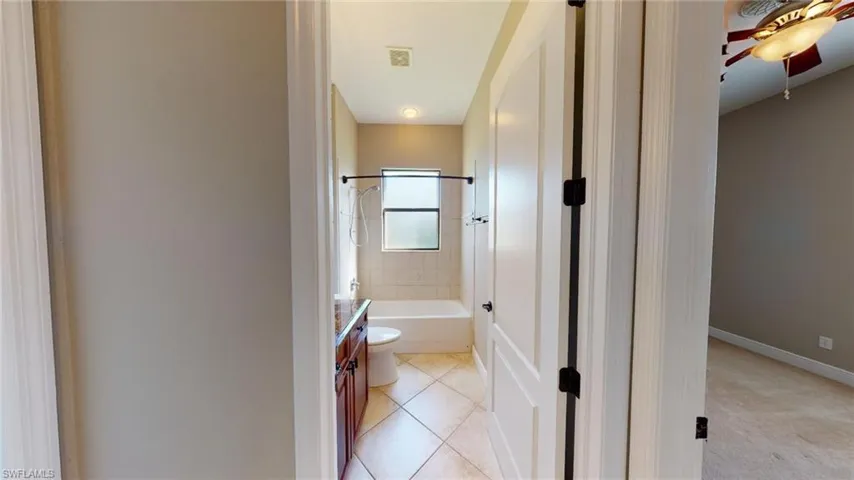 Full bathroom featuring tiled shower / bath, tile patterned floors, toilet, ceiling fan, and vanity