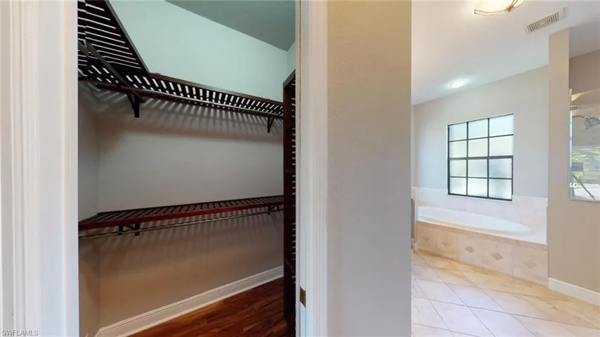 Walk in closet with light hardwood / wood-style flooring