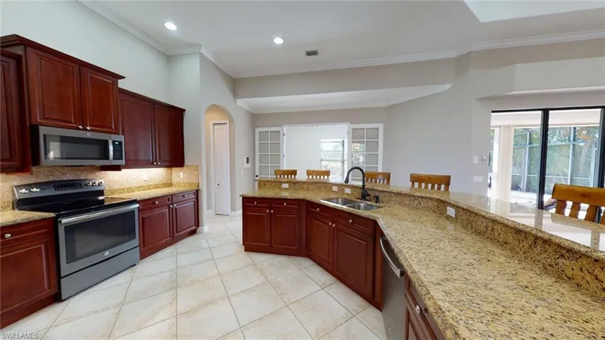 Kitchen featuring appliances with stainless steel finishes, plenty of natural light, sink, a kitchen bar, and tasteful backsplash