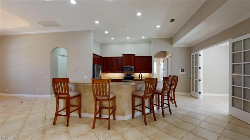 Kitchen with appliances with stainless steel finishes, light stone counters, kitchen peninsula, and a kitchen breakfast bar