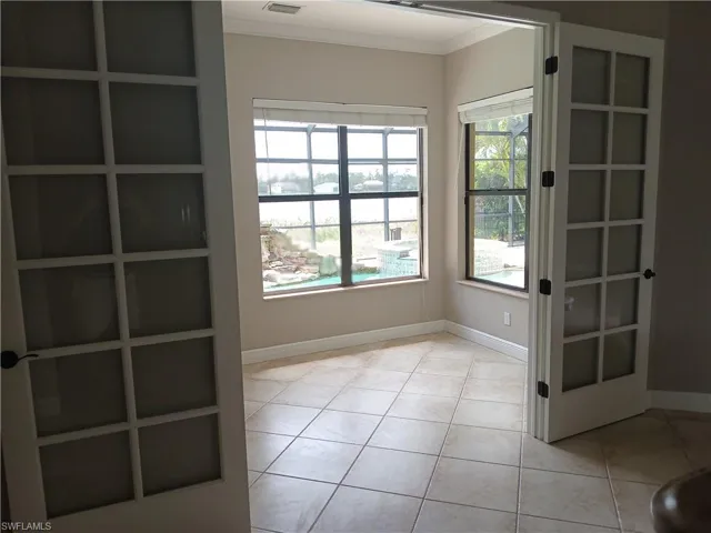 Tiled empty room featuring ornamental molding and a healthy amount of sunlight