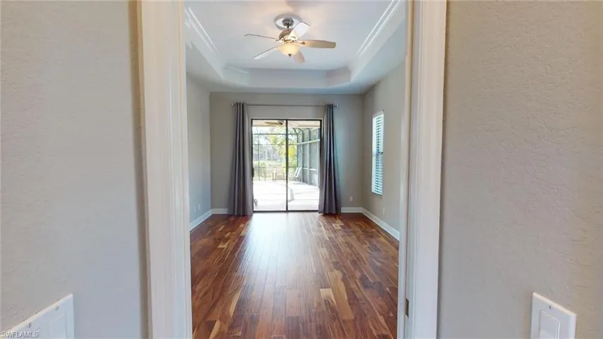 Entryway with ceiling fan, a raised ceiling, dark hardwood / wood-style flooring, and ornamental molding