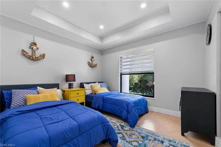 Tiled bedroom featuring a tray ceiling and recessed lighting