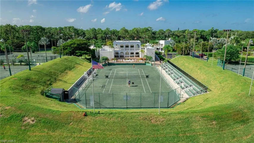 View of tennis court with view of wooded area