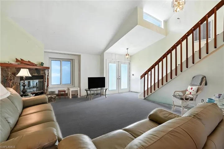 Carpeted living area with french doors, stairway, and a chandelier - Virtually Edited Image