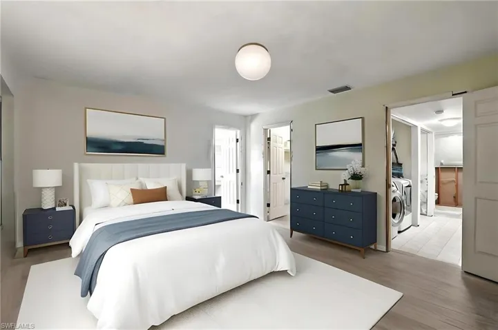 Bedroom 1 with separate washer and dryer, light wood-style floors, a walk in closet, and connected bathroom - Virtually Staged and Edited Image. first floor