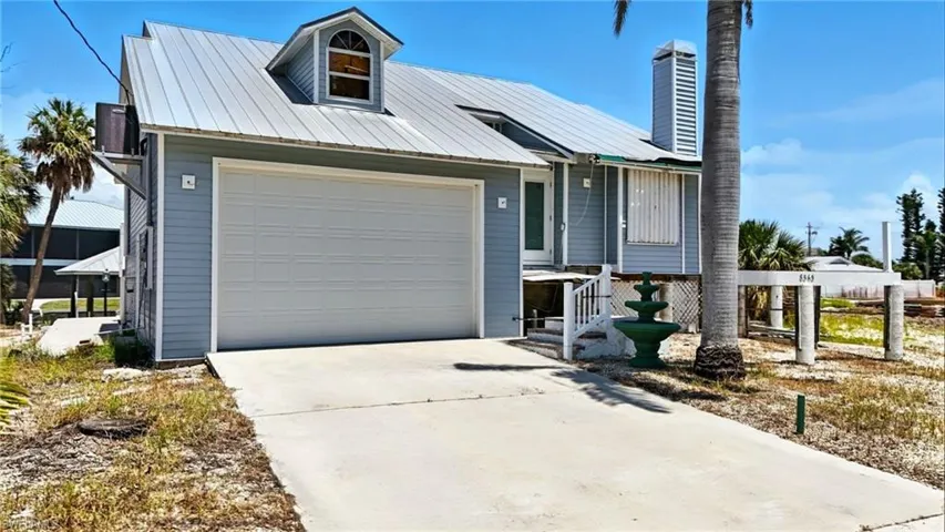 View of front facade featuring concrete driveway, a chimney, and a metal roof - Virtually Edited Image