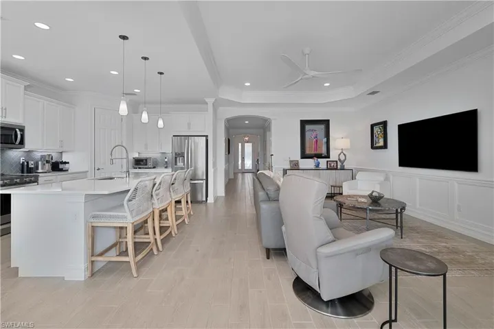 Living room with ceiling fan, sink, light hardwood / wood-style flooring, and ornamental molding