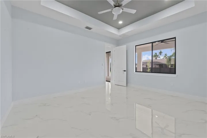 Tiled spare room featuring ceiling fan and a raised ceiling