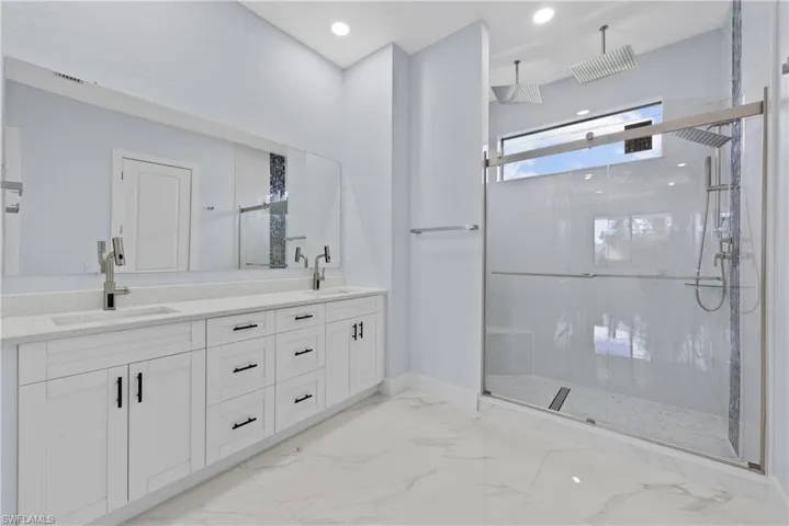 Bathroom with tile floors, an enclosed shower, large vanity, and dual sinks