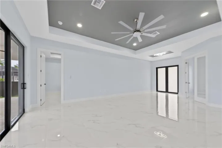 Empty room featuring ceiling fan, light tile floors, and a raised ceiling