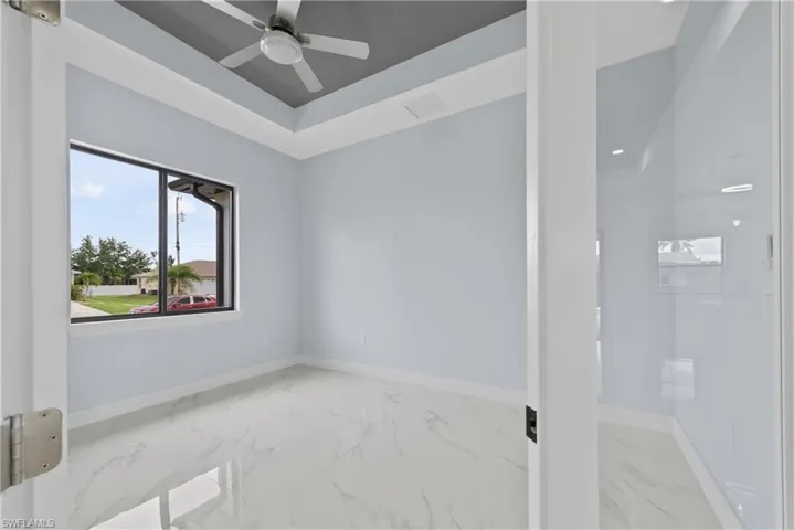 Unfurnished room featuring a tray ceiling, ceiling fan, and tile floors