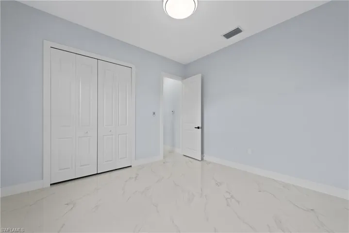 Unfurnished bedroom with a closet and light tile floors