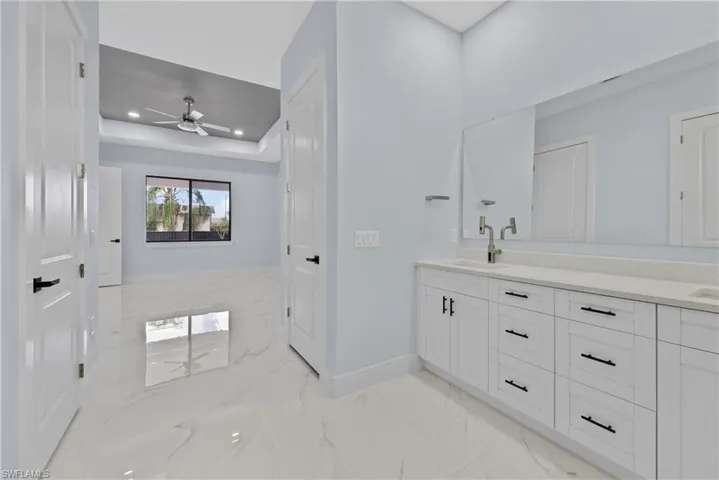 Bathroom featuring tile floors, ceiling fan, a raised ceiling, and vanity
