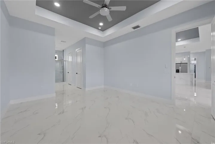 Tiled spare room with ceiling fan and a raised ceiling