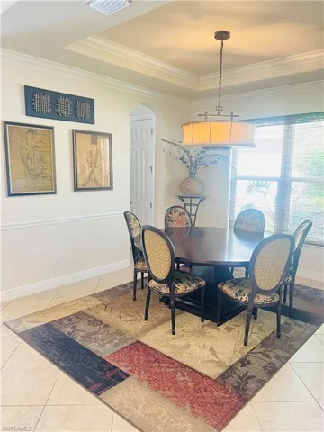 Tiled dining space with a raised ceiling and ornamental molding