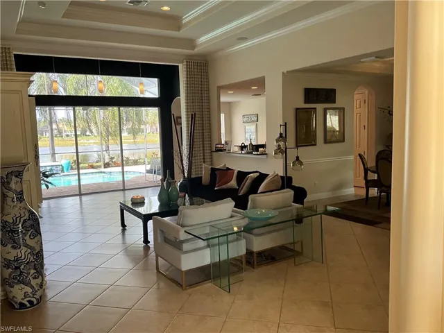Tiled living room featuring crown molding, a raised ceiling, and a towering ceiling