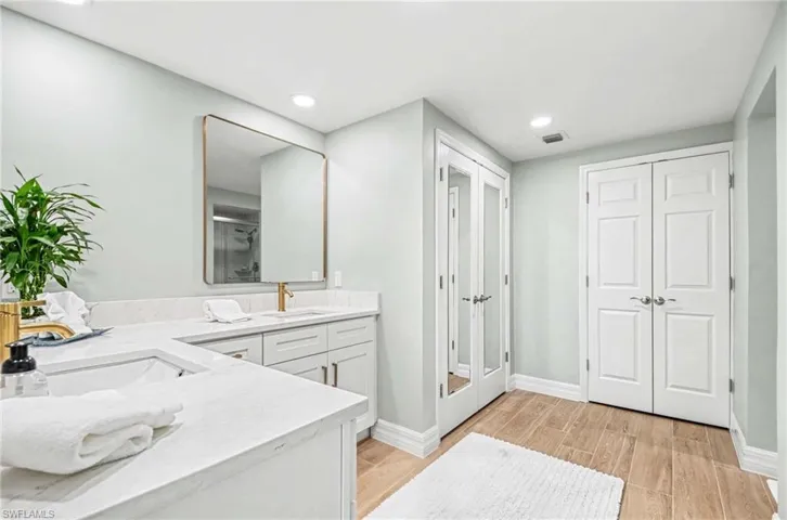 Bathroom with double vanity, light wood finished floors, a shower stall, a closet, and recessed lighting