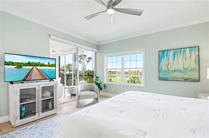 Bedroom with access to exterior, a water view, multiple windows, crown molding, and wood finished floors
