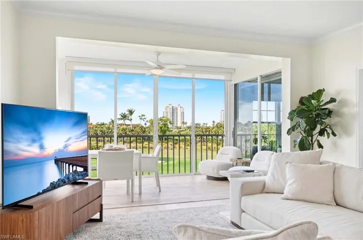 Living room with wood finished floors, ornamental molding, plenty of natural light, ceiling fan, and a city view