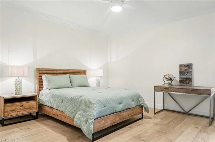 Bedroom featuring ornamental molding, light wood finished floors, and a ceiling fan