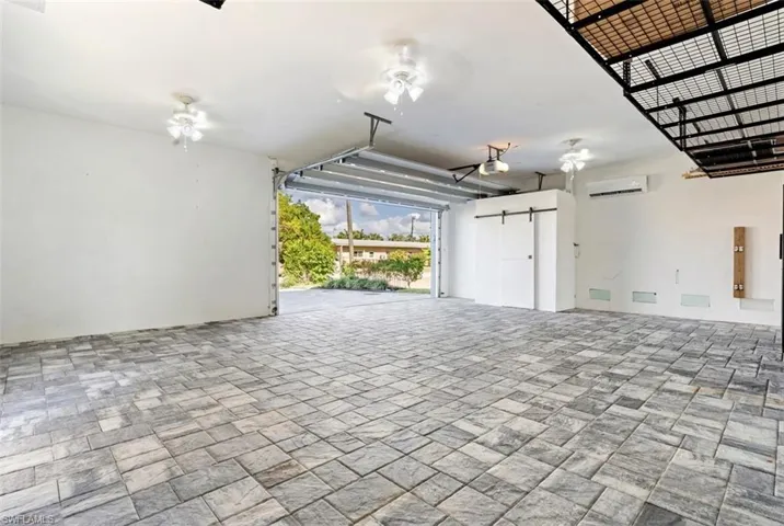 Garage featuring ceiling fan, a wall unit AC, and a garage door opener