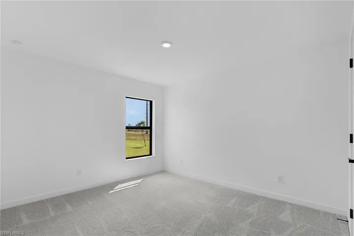 Spare room featuring light carpet and baseboards