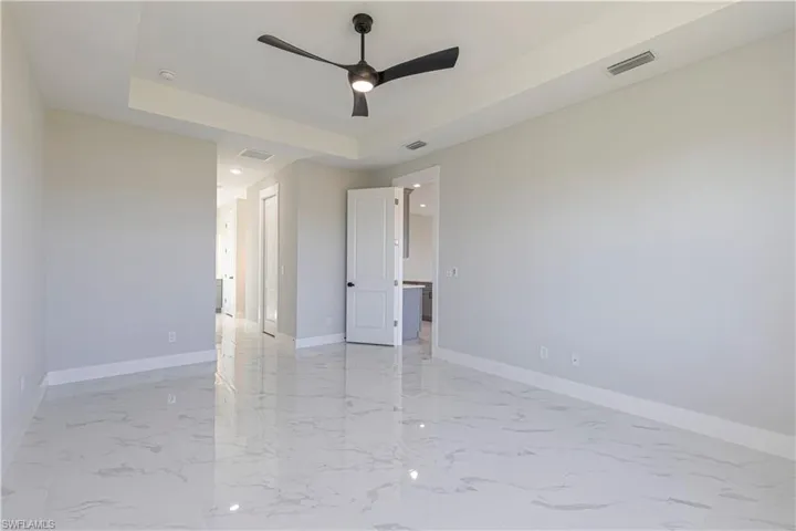 Unfurnished bedroom featuring a tray ceiling, ceiling fan, recessed lighting, and a closet