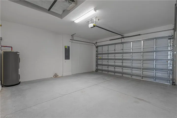 Garage with water heater, electric panel, and a textured wall