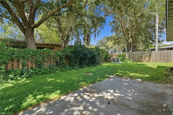 Concrete patio with green ground cover, wood privacy fencing, and mature trees