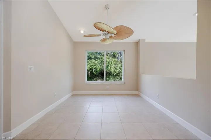 Tiled spare room featuring ceiling fan and vaulted ceiling