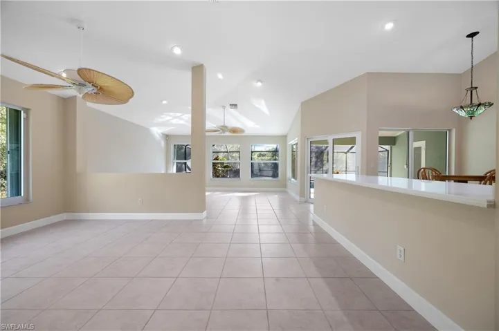 Unfurnished living room with light tile patterned floors, vaulted ceiling, and ceiling fan