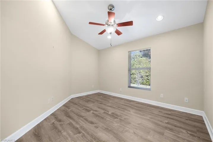 Empty room with hardwood / wood-style floors, vaulted ceiling, and ceiling fan