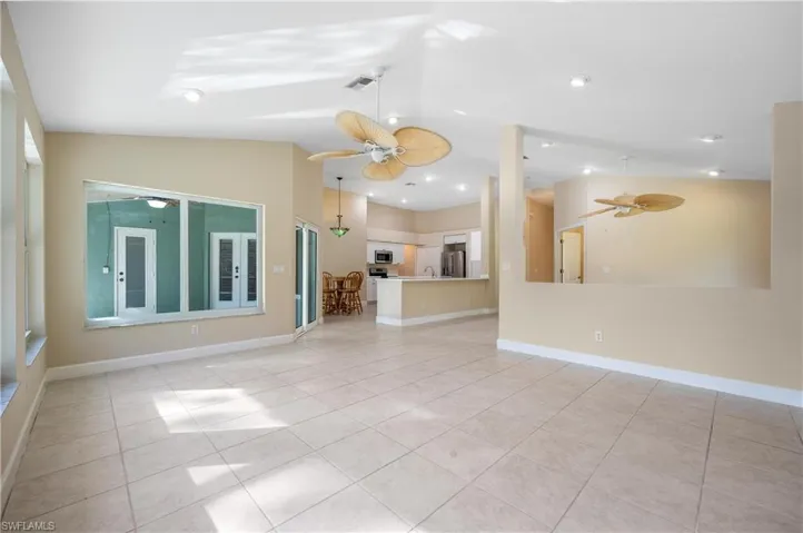 Unfurnished living room featuring lofted ceiling, sink, light tile patterned flooring, and ceiling fan