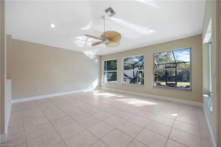 Empty room featuring ceiling fan, vaulted ceiling, and light tile patterned floors