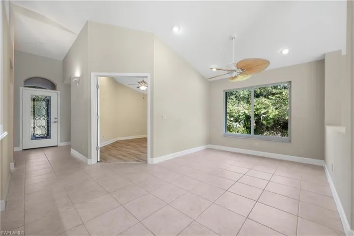 Tiled spare room featuring lofted ceiling and ceiling fan