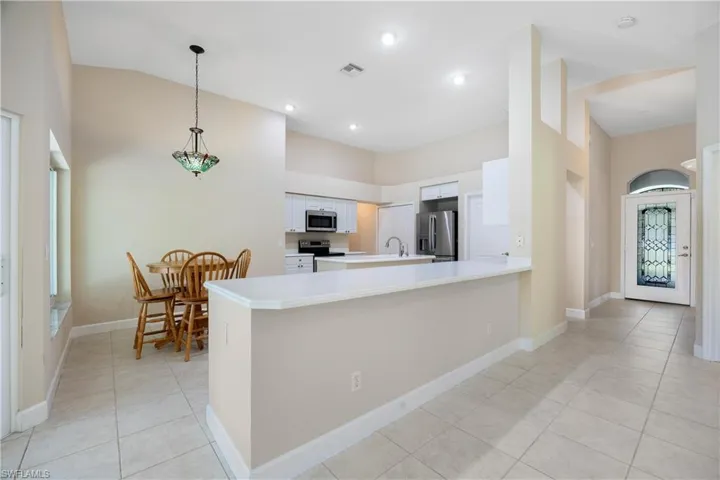 Kitchen with white cabinetry, high vaulted ceiling, stainless steel appliances, and kitchen peninsula