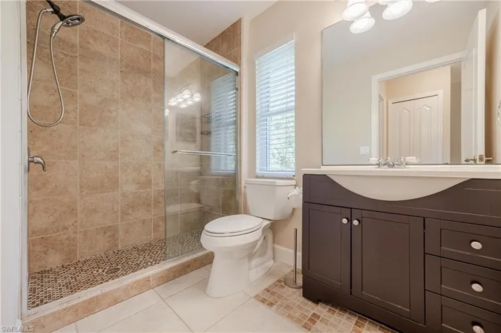 Bathroom featuring vanity, toilet, tile patterned floors, and a shower with door