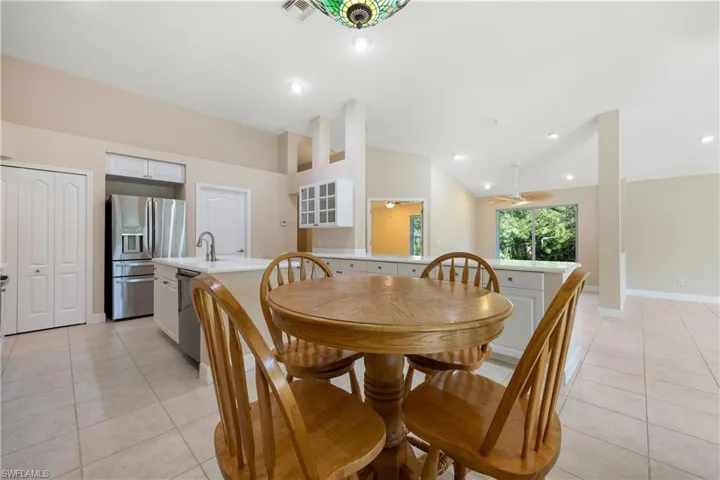 Dining room featuring lofted ceiling, sink, light tile patterned flooring, and ceiling fan