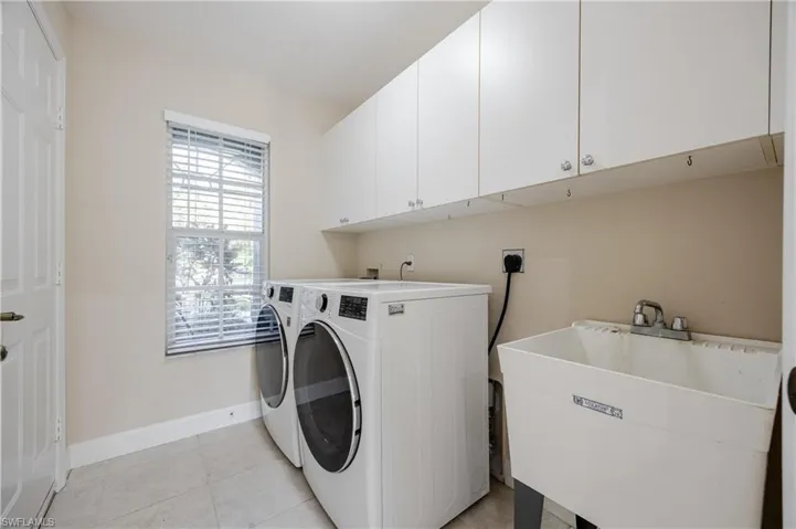 Washroom with cabinets, independent washer and dryer, a healthy amount of sunlight, and sink