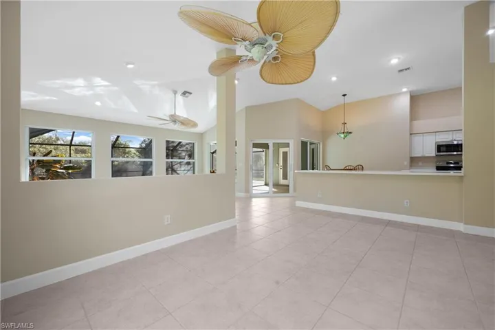 Unfurnished living room with ceiling fan, high vaulted ceiling, and light tile patterned floors
