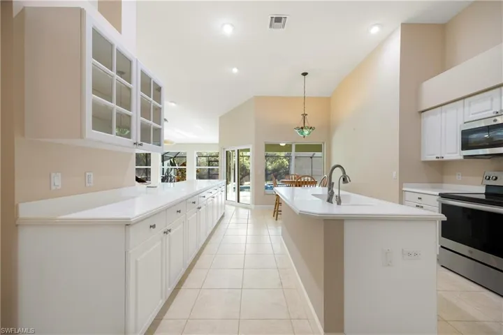 Kitchen featuring sink, appliances with stainless steel finishes, hanging light fixtures, and white cabinets