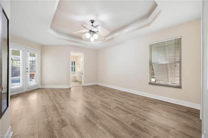 Unfurnished room with french doors, ceiling fan, light wood-type flooring, and a raised ceiling