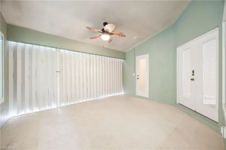 Empty room featuring french doors, vaulted ceiling, and ceiling fan