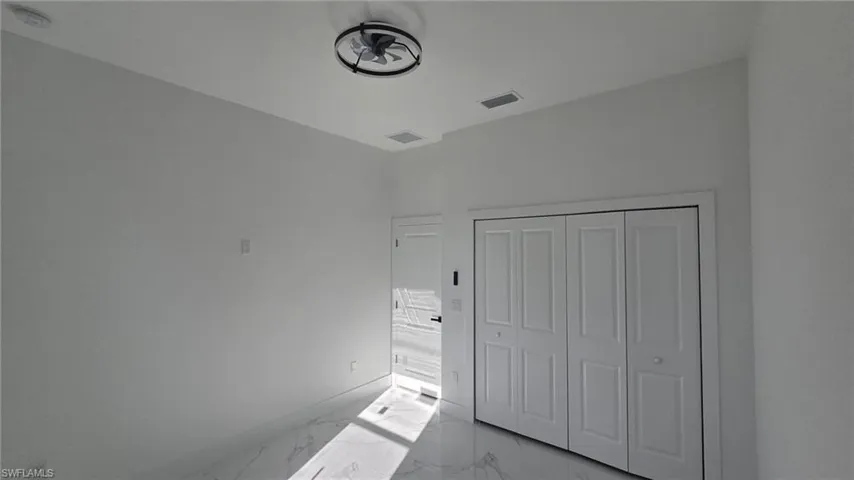 Unfurnished bedroom with light marble finish floors and a closet