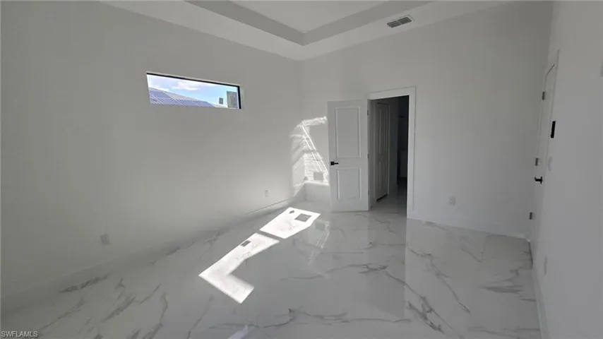Unfurnished bedroom featuring multiple windows and light marble finish floors