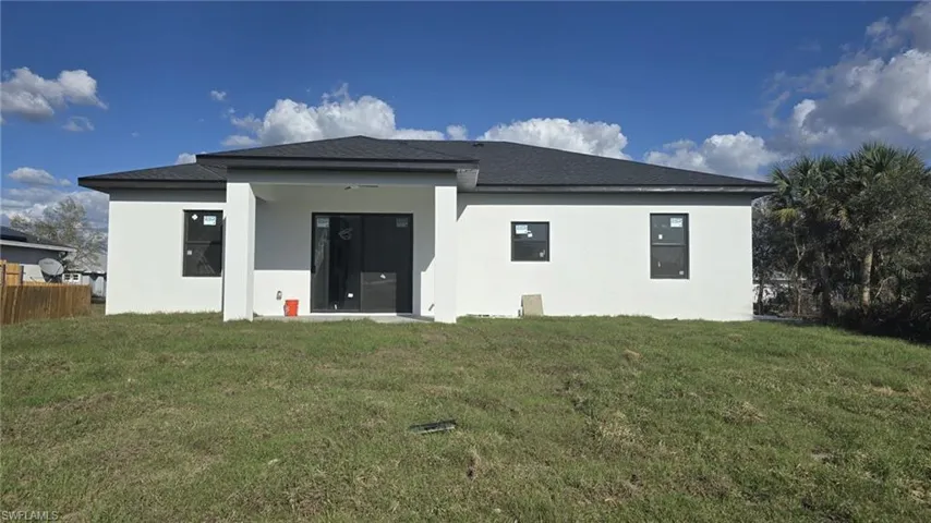 Back of house with stucco siding, roof with shingles, and a patio
