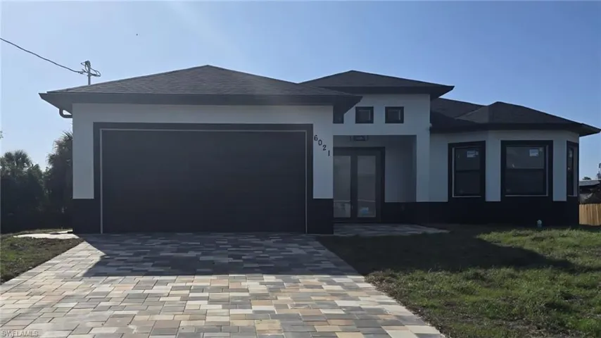 Prairie-style house featuring a garage, decorative driveway, stucco siding, a front yard, and roof with shingles